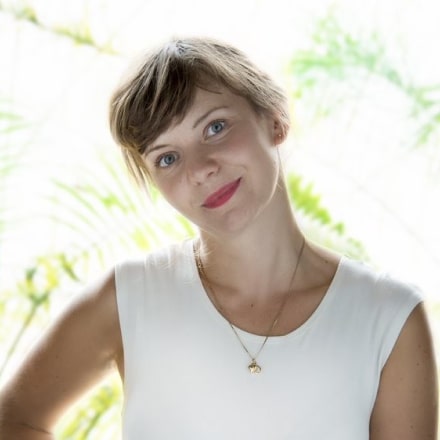 Headshot of Ola Michalec against a blurred background of green plants